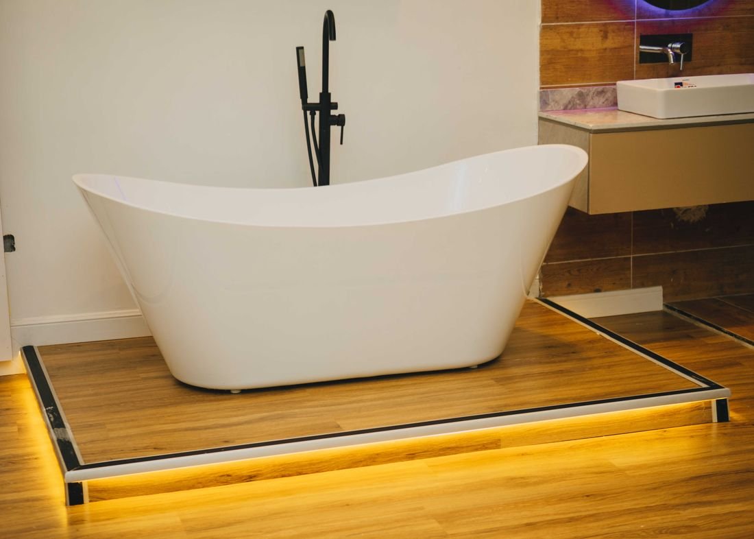A freestanding bath lit from below on a raised timber platform