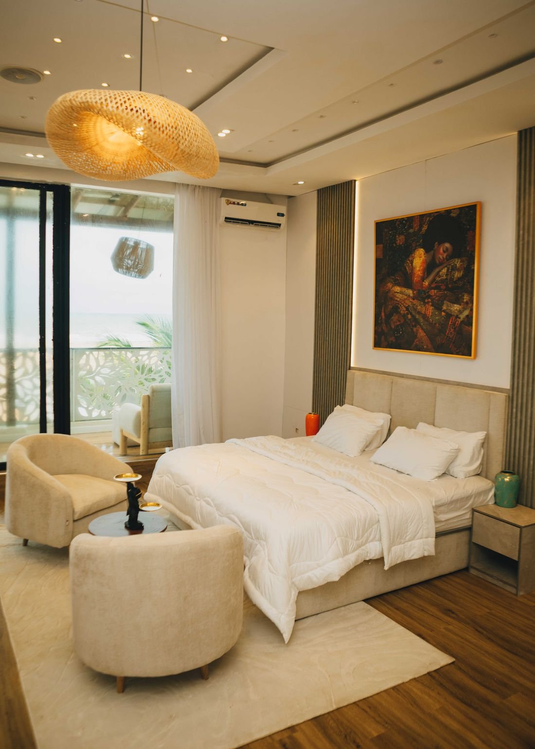 A bedroom with a woven pendant light and a seating area by the window