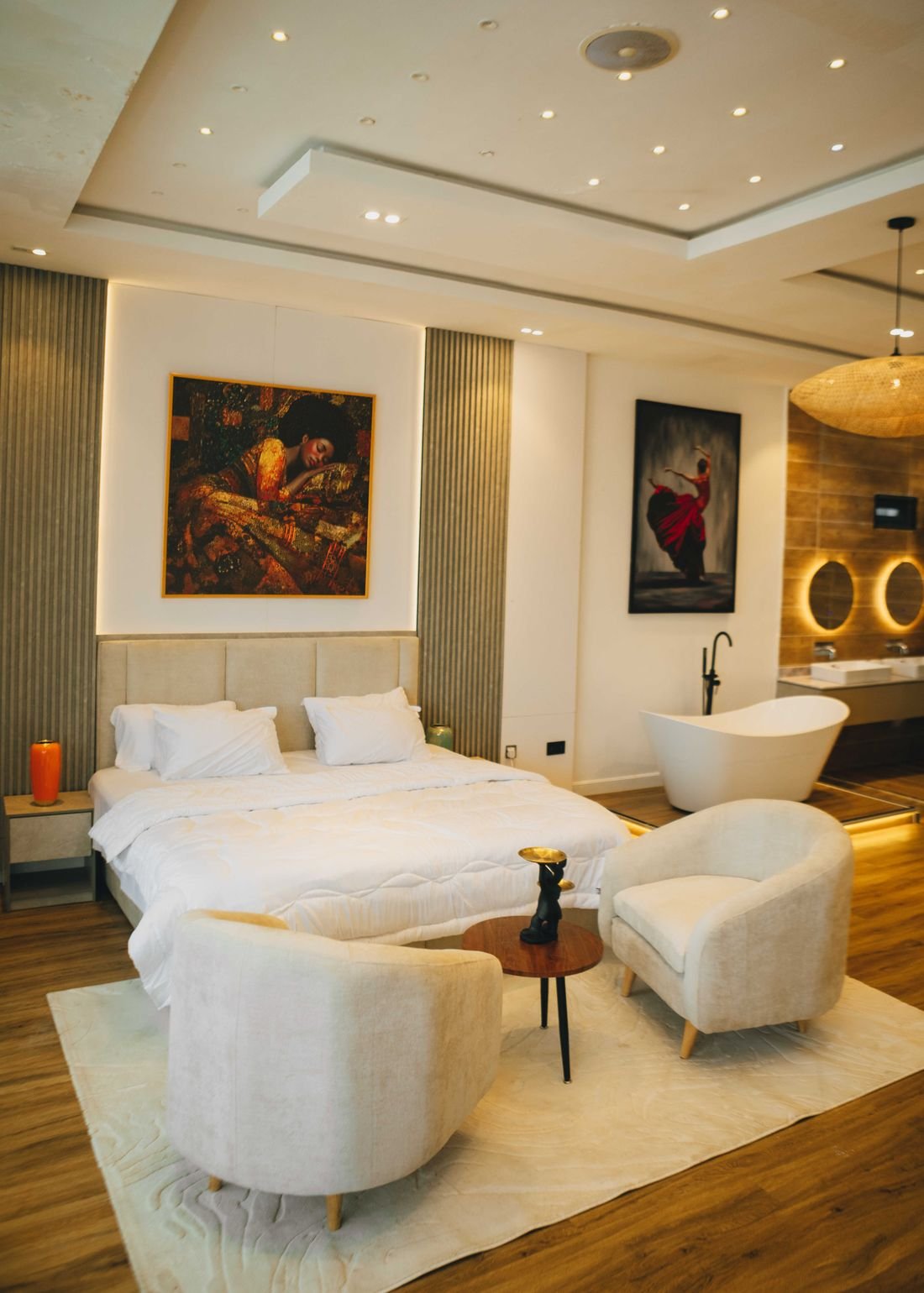 A bedroom with paired armchairs and a low round table