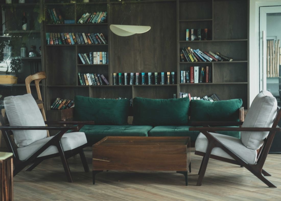 The library lounge with a deep green sofa and full bookshelves