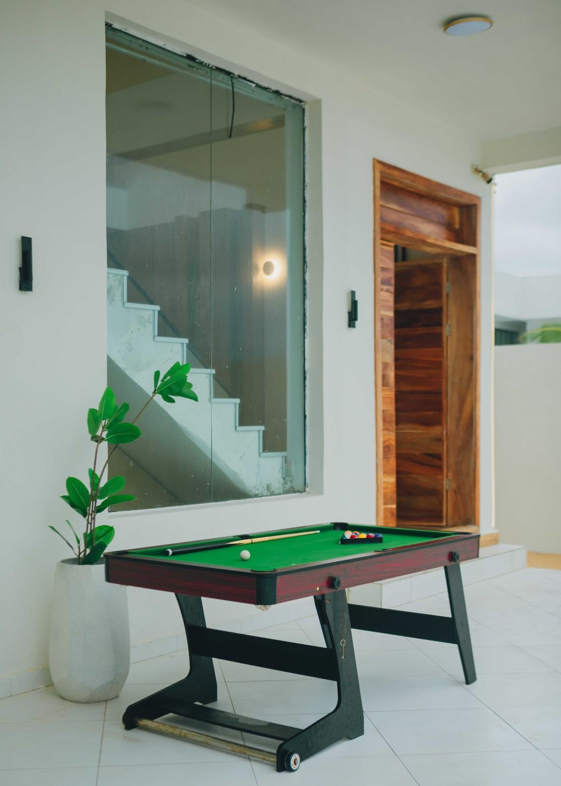 A pool table set up on the ground floor beside the staircase