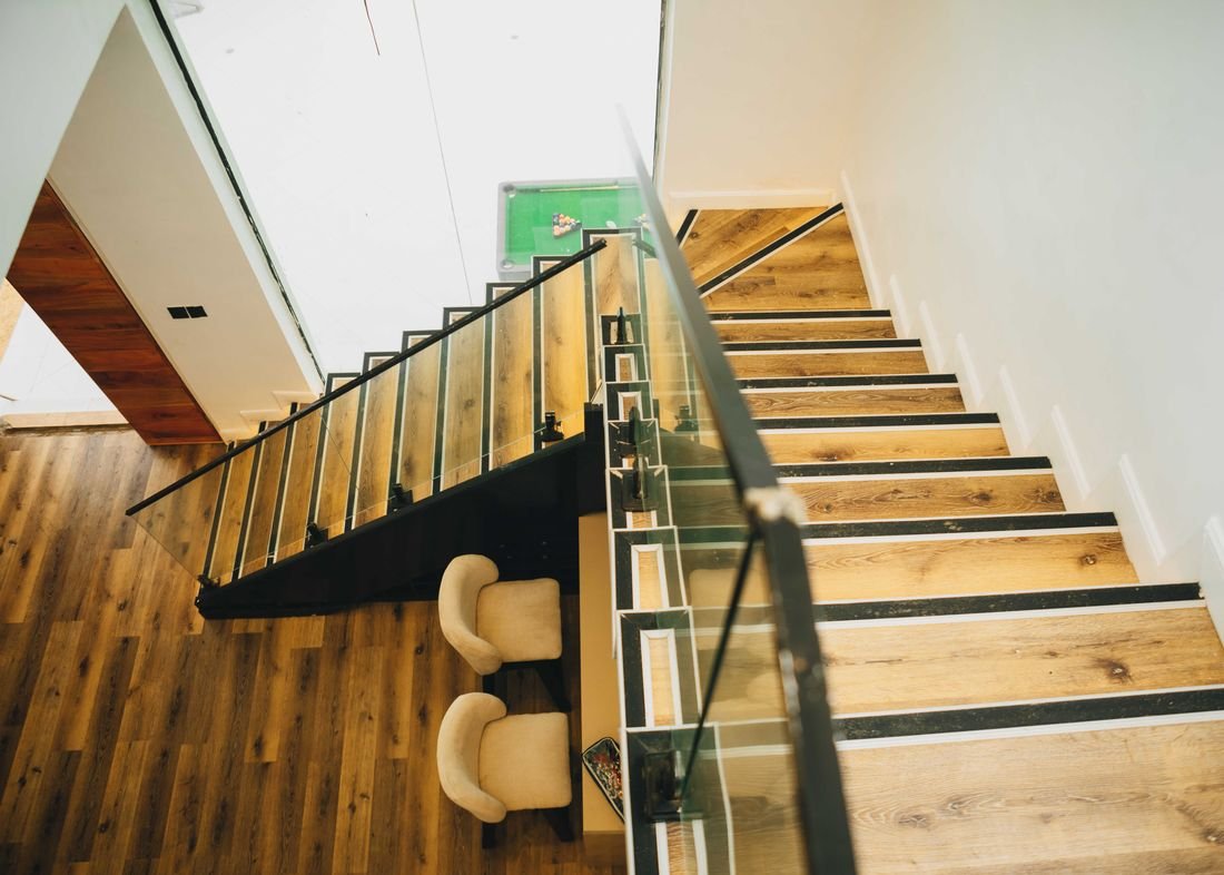 An open timber staircase with a glass balustrade