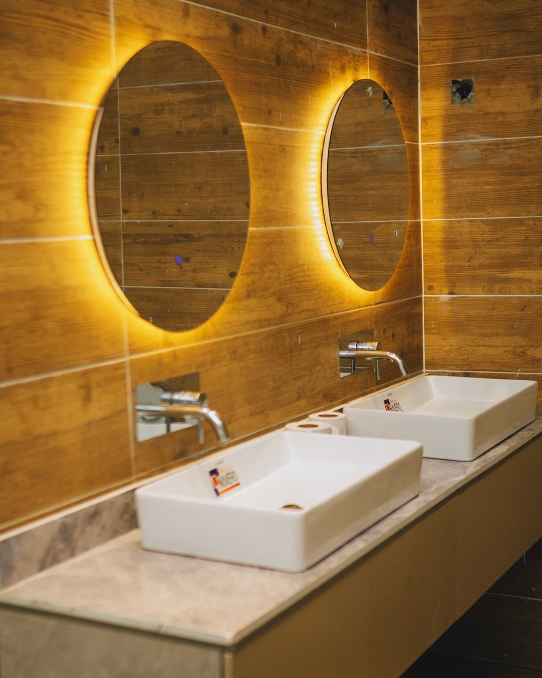 Twin basins beneath backlit oval mirrors